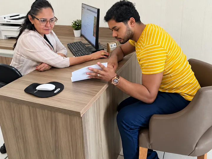 Suzane Salvador e um cliente conferindo juntos um documento sobre a mesa do escritório
