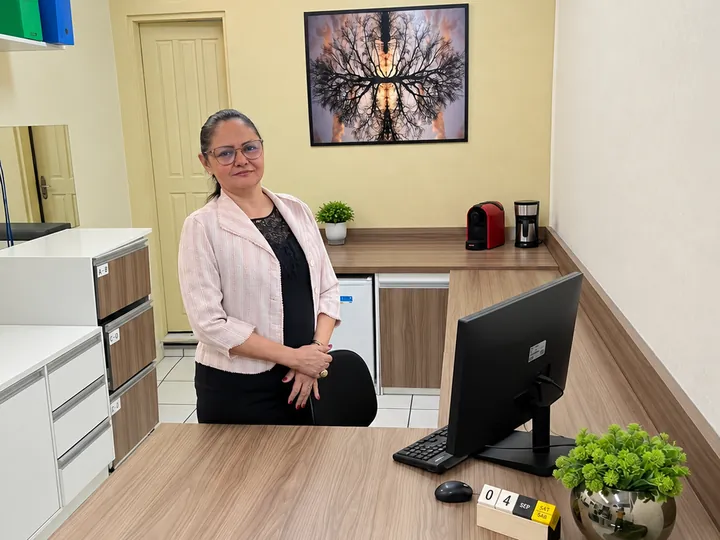 Suzane Salvador em pé atrás da mesa de trabalho, no escritório da Parceria