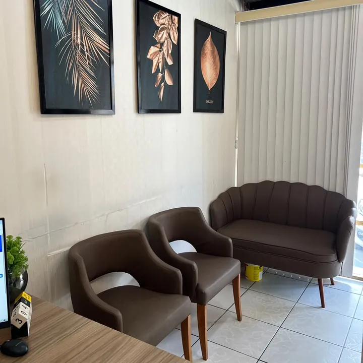 Recepção do escritório da Parceria, com sofá e poltronas marrons e quadros de folhas douradas na parede